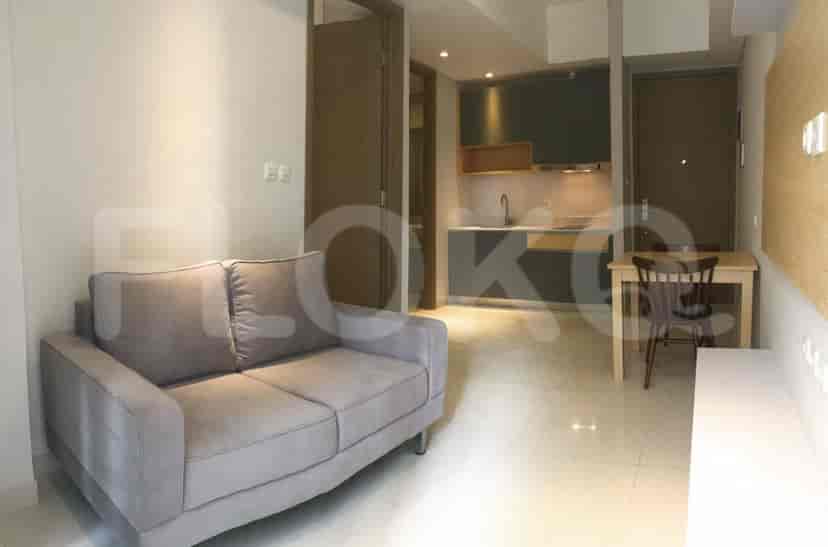 Living room with a grey sofa, and an adjacent kitchen area.