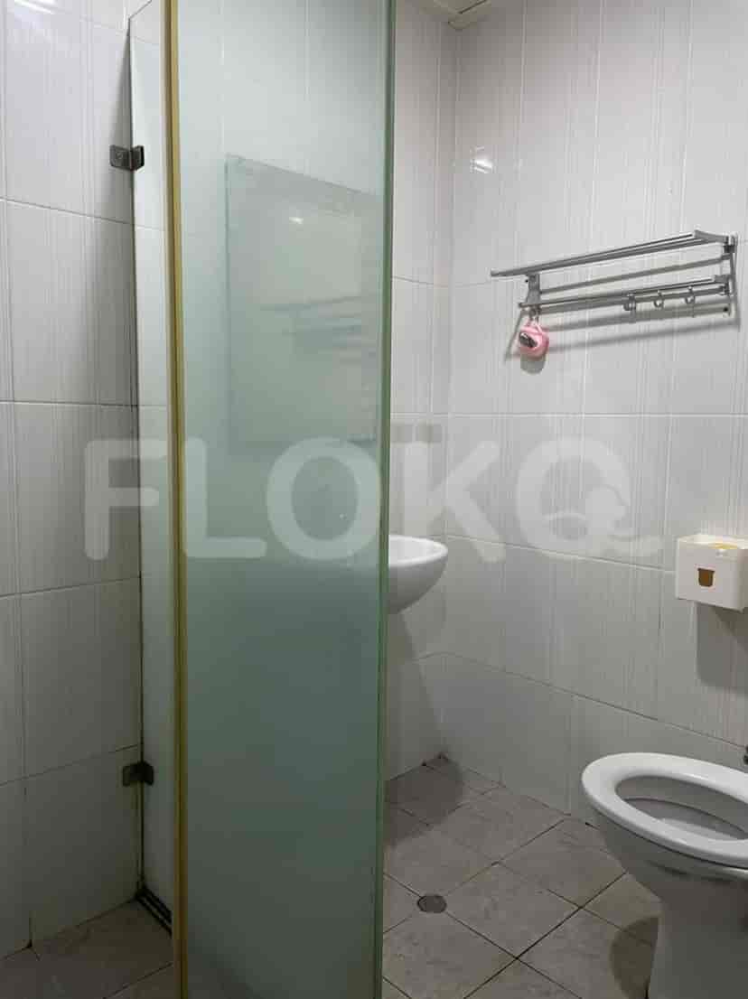 A small, clean bathroom with a glass shower enclosure, white tile walls, and a toilet.