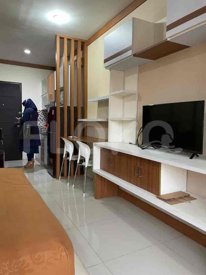 A small apartment living area with a kitchenette, dining space, and entertainment center.