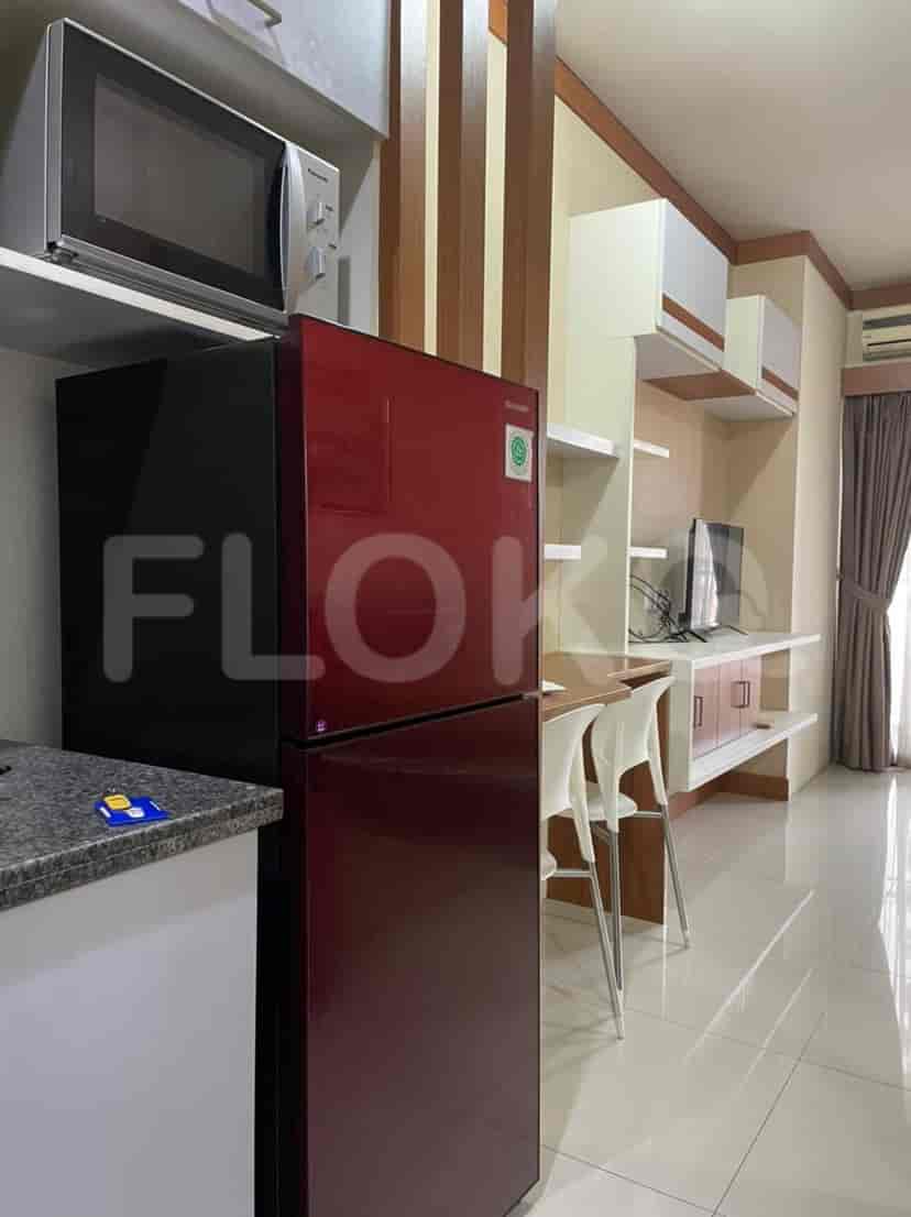 Kitchen area with a fridge, shelves, and breakfast bar with bar stools.