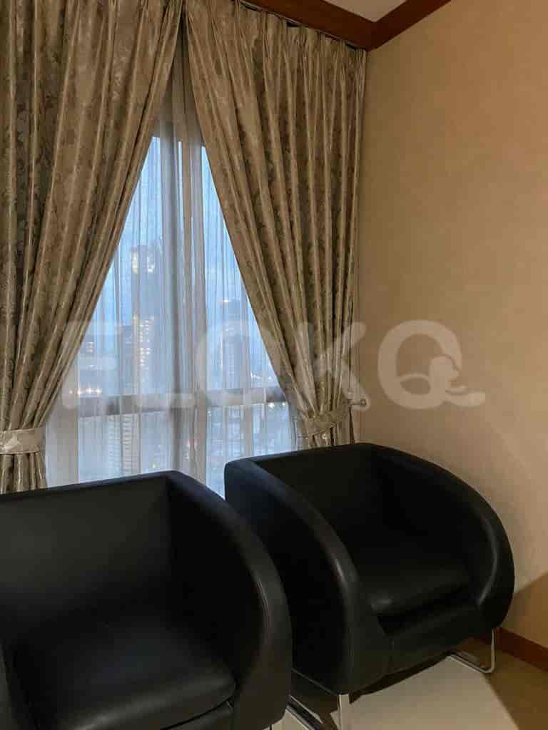 A seating area with two black chairs and curtains.