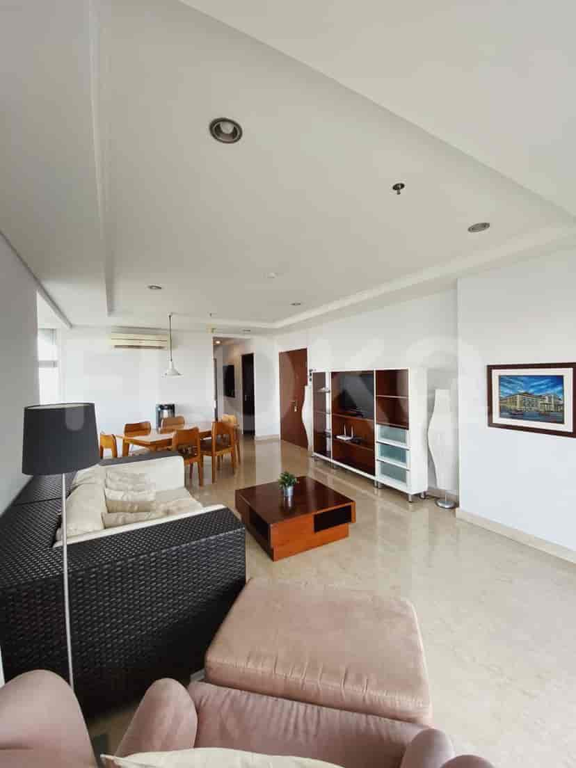 Spacious living room with a dark-colored sofa, wooden dining table, and access to a balcony with city views.