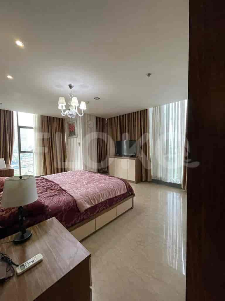A master bedroom with a large bed, elegant decor and a large window.