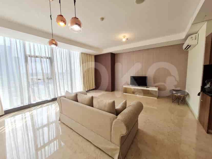 Spacious living room with a sofa, a smart TV, and large windows with curtains.