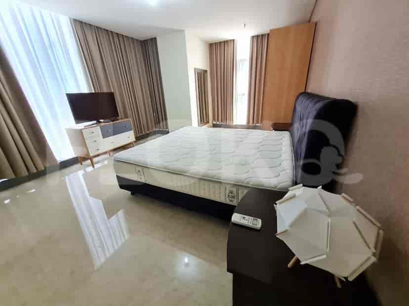 A bedroom with a bed, a TV, and a side table with a lamp