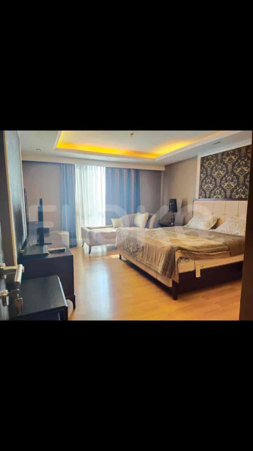 Kamar tidur utama mewah dengan tempat tidur, area duduk, dan TV pintar.