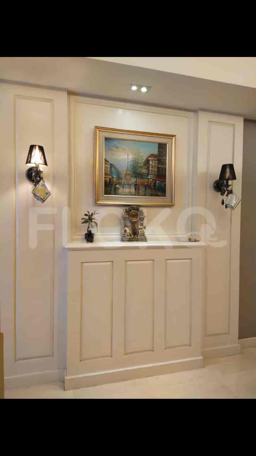 Area pintu masuk yang elegan dengan lukisan, pencahayaan sconce, dan konsol dekoratif.