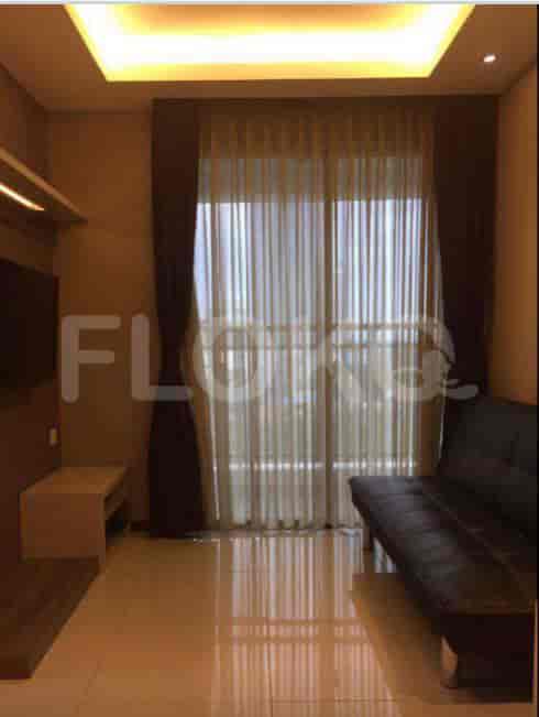 Compact living area with a black leather sofa and a large window.