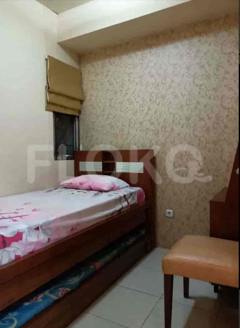 A compact bedroom with a single bed, small window, and patterned wallpaper.