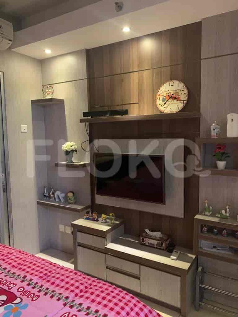 A living room with a TV, wall-mounted shelves, and a clock.
