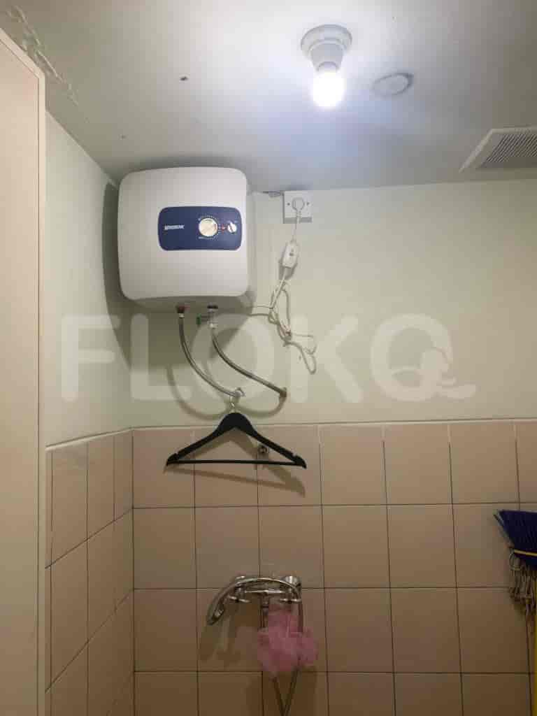 A small bathroom with a water heater mounted on the wall, shower and tiled walls.