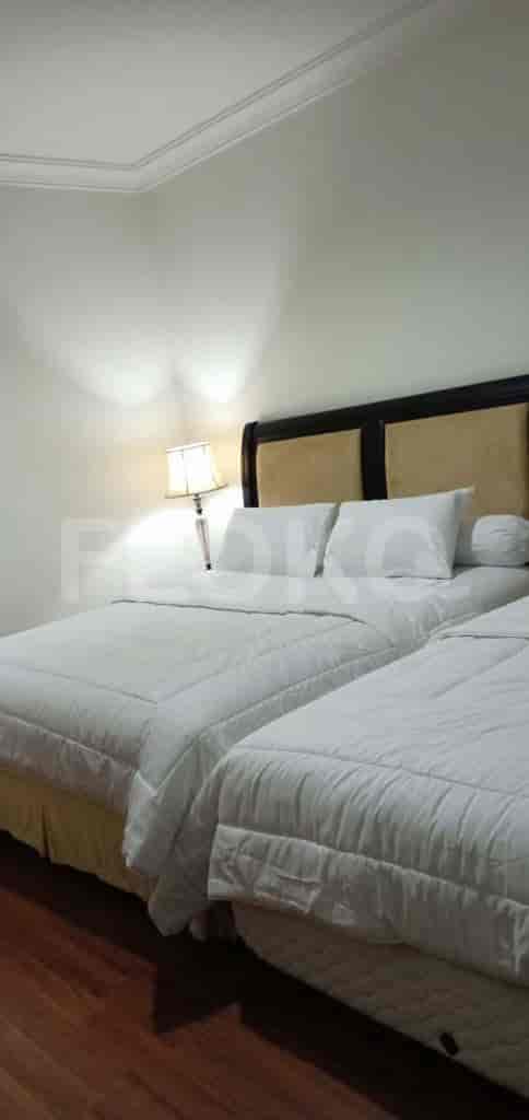 A bedroom with twin beds and a bedside lamp.