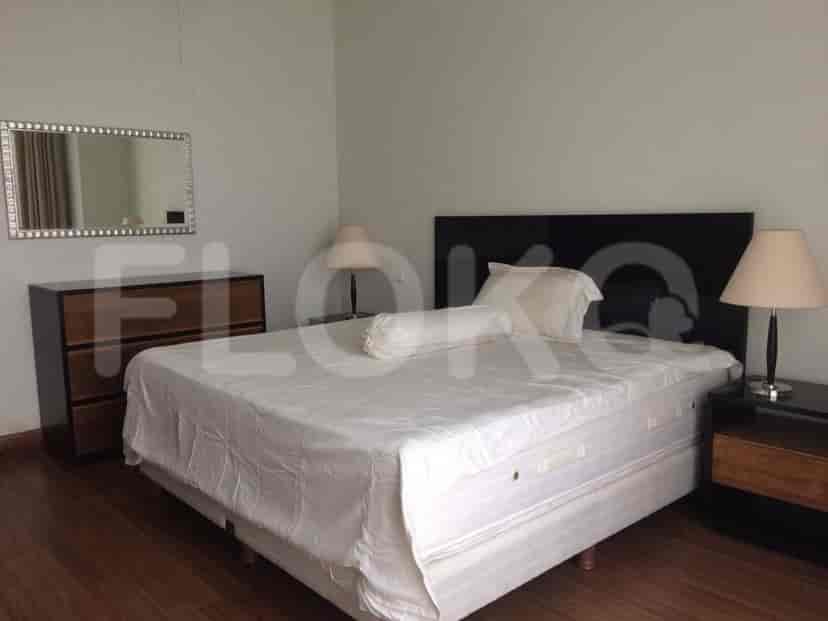 A bright bedroom featuring a king-sized bed, a nightstand with a lamp, and a dresser with a mirror.