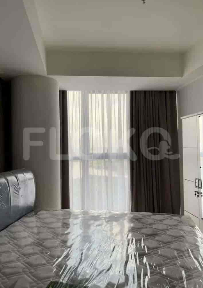 A modern bedroom featuring a bed with a plastic cover, large window with curtains, and wardrobe.