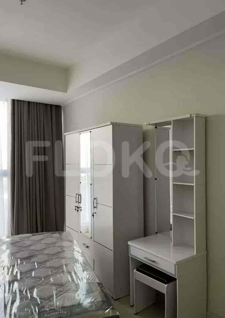 A well-lit bedroom featuring a bed with a plastic cover, a large wardrobe, and a vanity table.