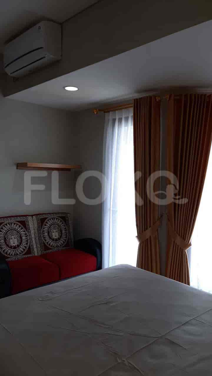 A bedroom with a bed, sofa, and window with curtains.