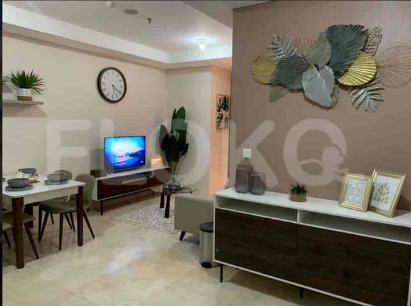 A furnished living room with a dining area, a TV, and decorative elements.