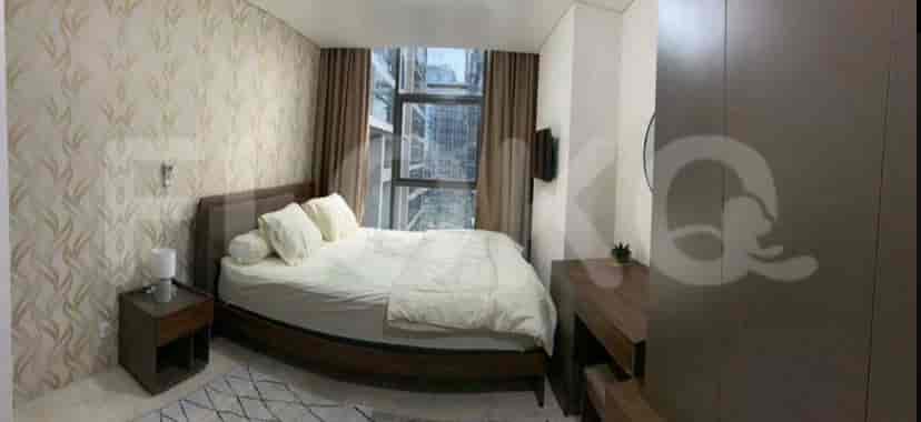 A modern bedroom featuring a large bed with neutral bedding, a desk, and a cityscape view.