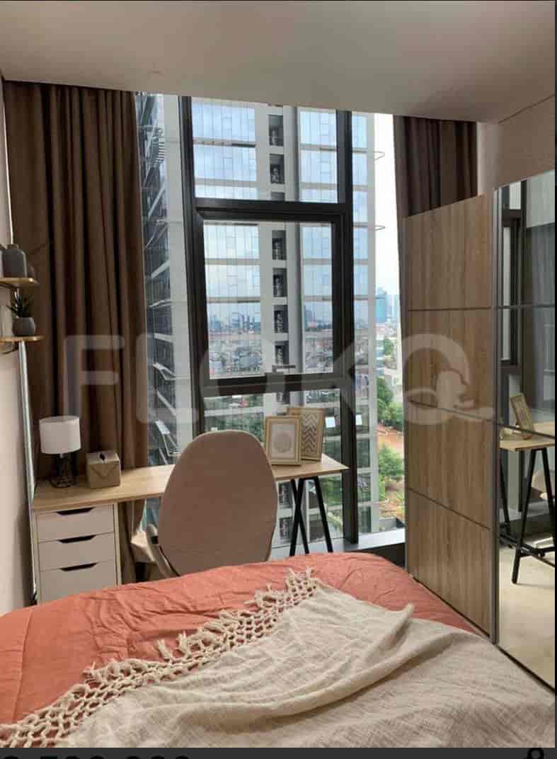 A bedroom with a double bed, desk, and cityscape view.