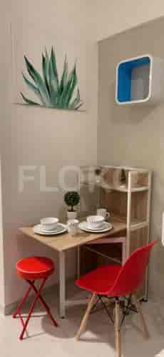 A small dining area featuring a table, a stool, and a red chair.
