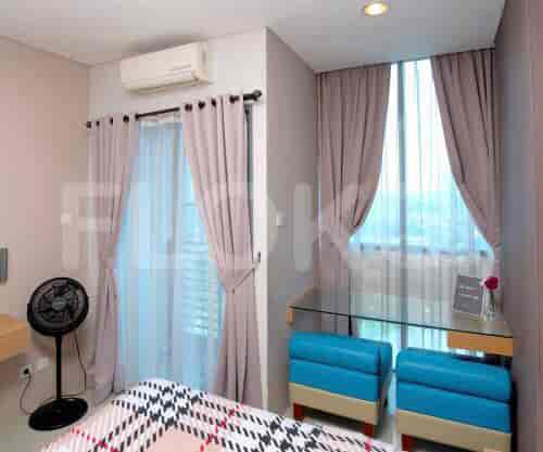 A bedroom with a bed, curtains, and a fan.