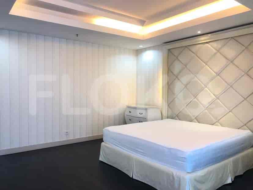 A master bedroom with a bed featuring a cushioned headboard and a dressing table.