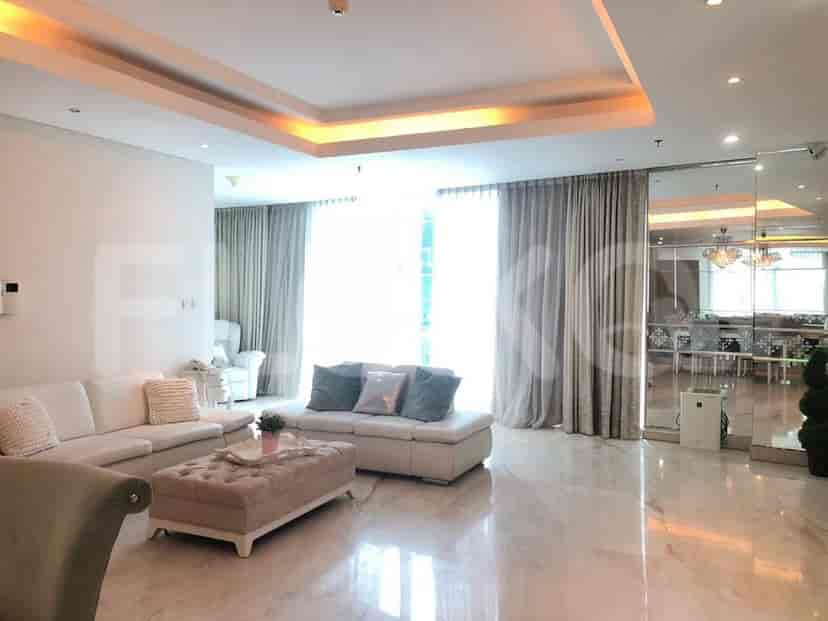 A living room with a sofa, ottomans, and large windows.