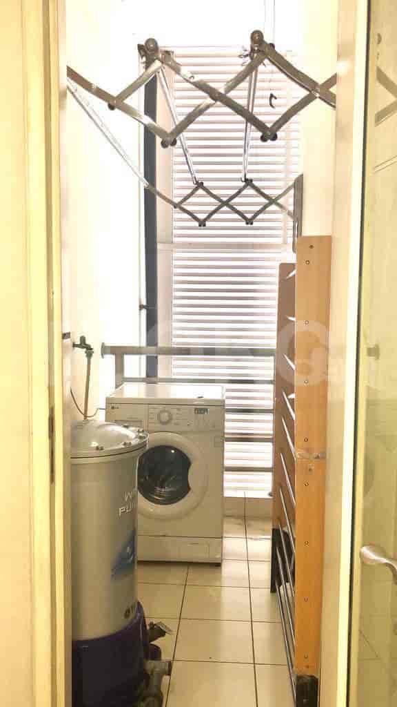 A laundry room with a washing machine and drying rack.