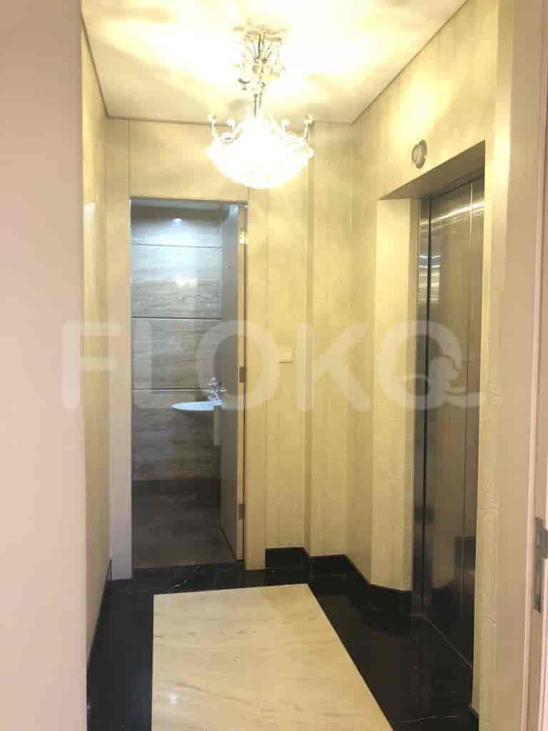 A hallway with an elevator and a glimpse into a bathroom.