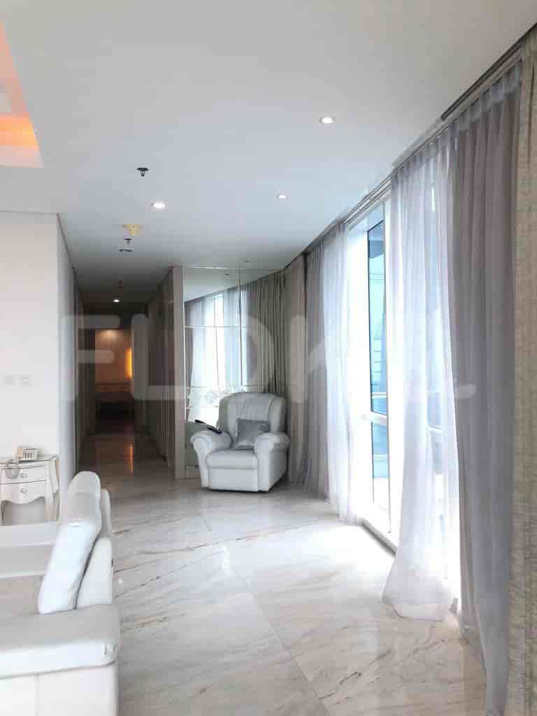 A hallway with large windows and a glimpse of a living area.