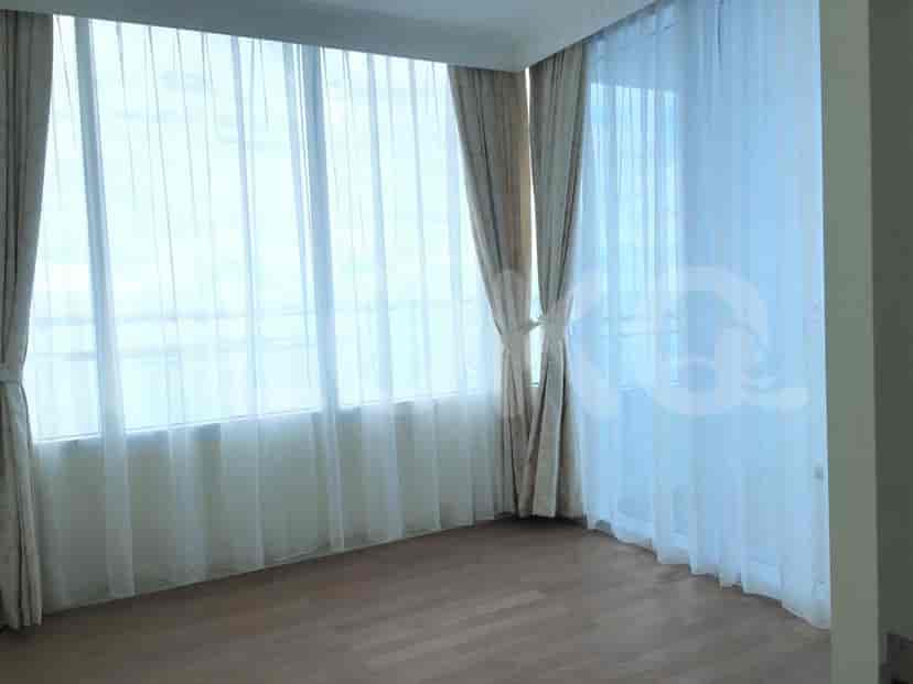 An empty room with a large window and curtains.