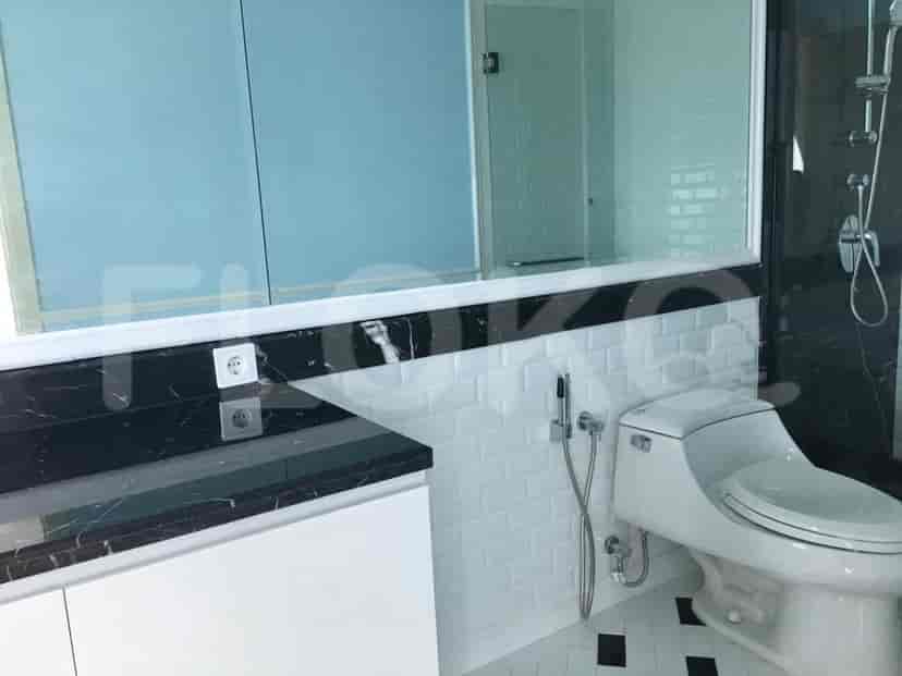 A bathroom with a toilet and vanity with a large mirror.