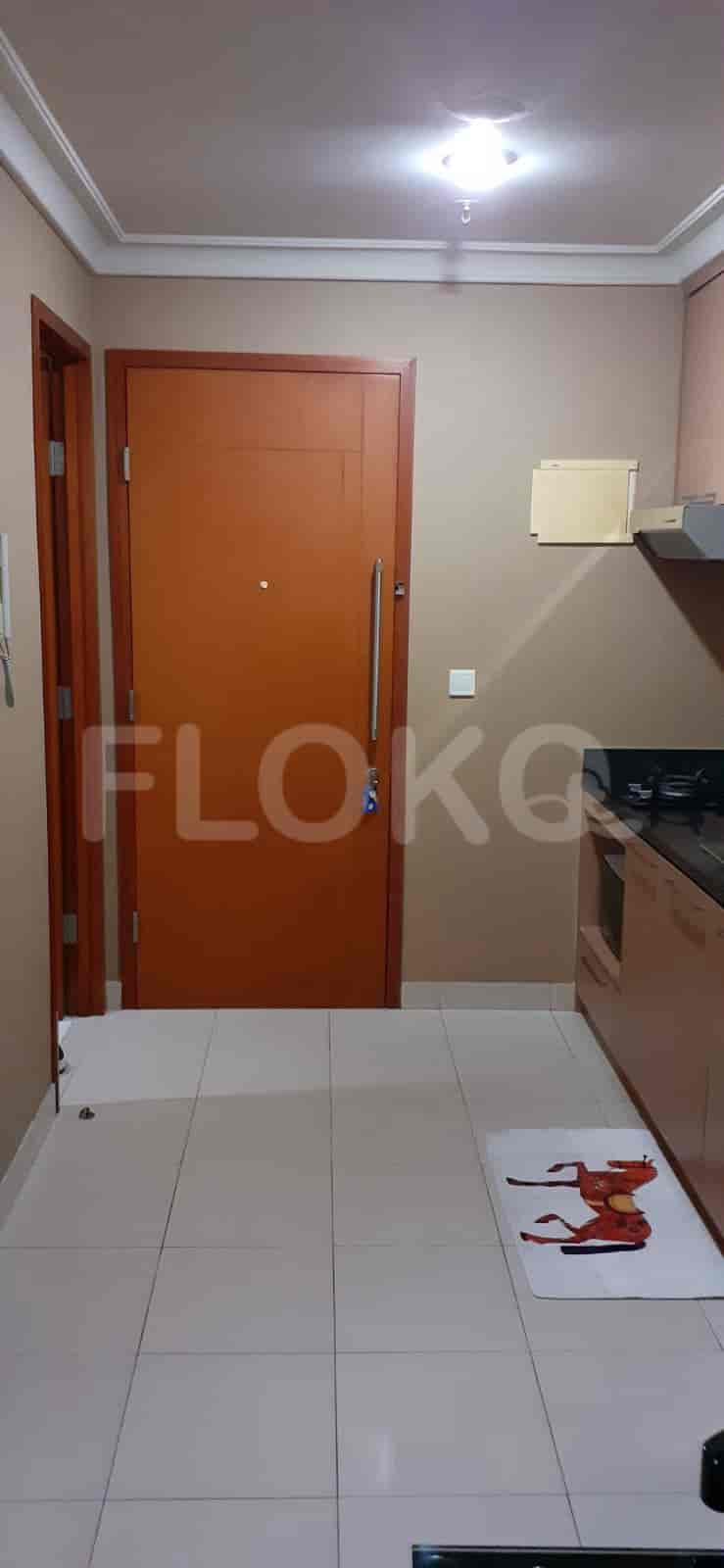 The entrance to a unit with a door, and the start of a kitchen.