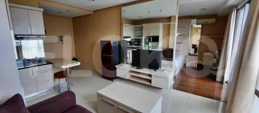 Studio apartment featuring a compact kitchen, a dining table, and a living area with a sofa and TV.