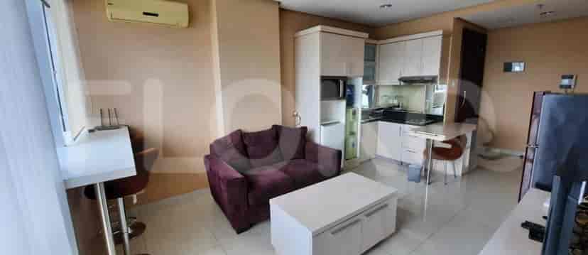 View of the combined living area with a sofa, TV and kitchen.