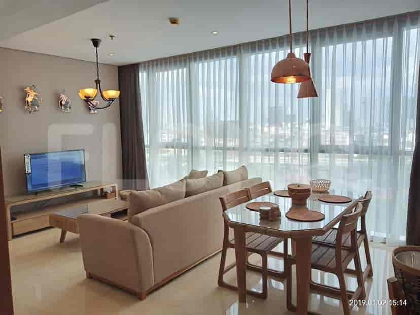 A living room featuring a sofa, dining table, and large windows.