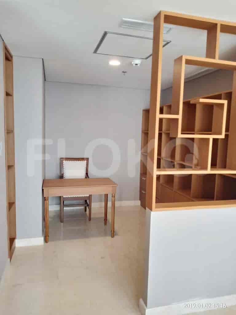 A home office with wooden shelves, a writing desk, and a chair.