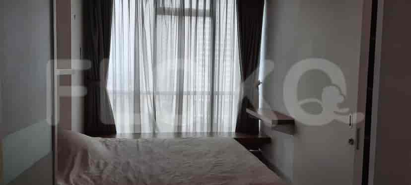 A bedroom with a large bed, sheer curtains, and a built-in shelf.