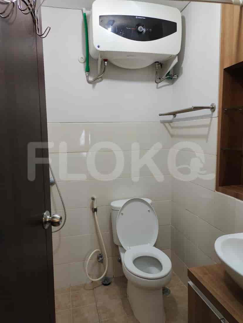 A small bathroom with a white toilet, shower, and a water heater.