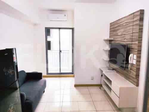 Living room with a TV mounted on a decorative wooden panel, sofa, and access to a balcony.