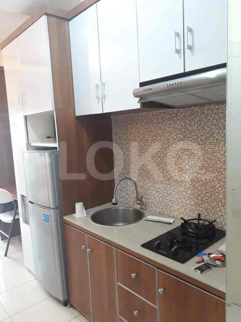 A compact kitchen with wooden cabinets, a stainless steel sink, and a gas stove.