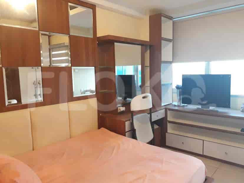 A bedroom with a bed featuring a mirrored wall, a work desk, and a TV.