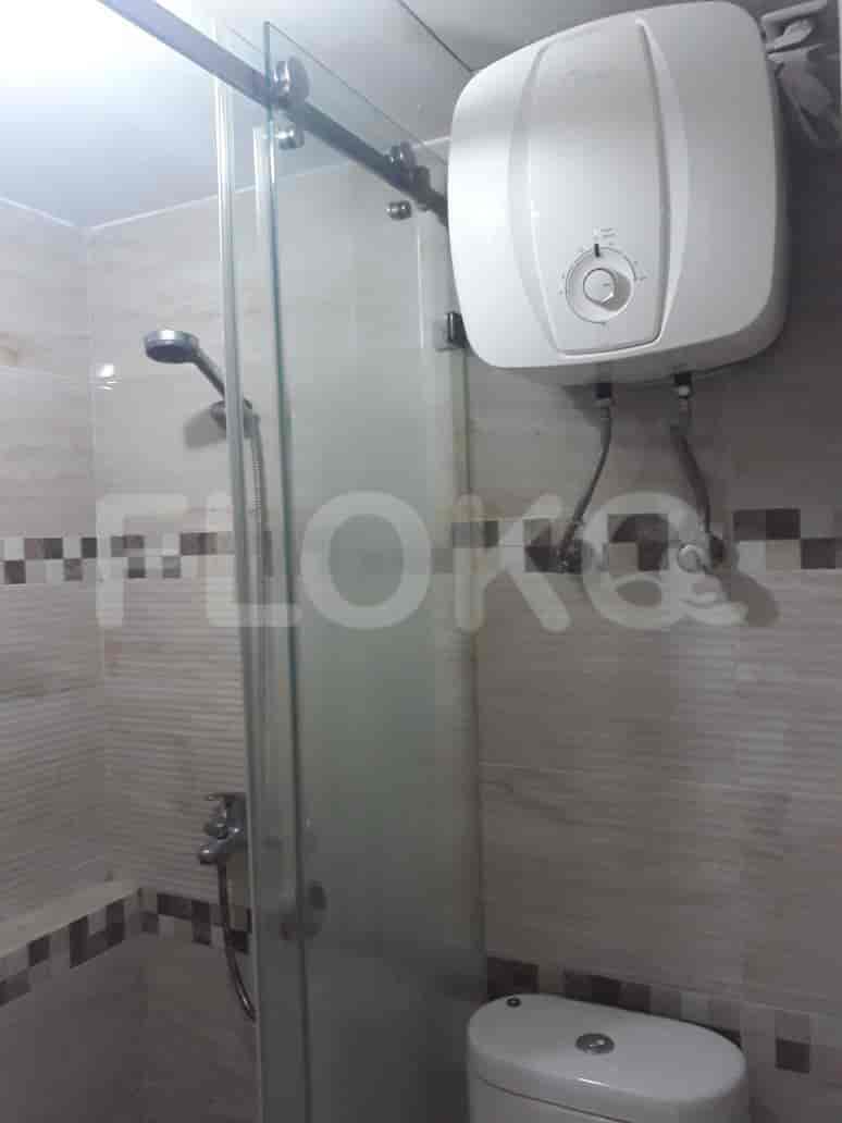 A clean bathroom with a glass shower enclosure, a wall-mounted water heater, and tiled walls.