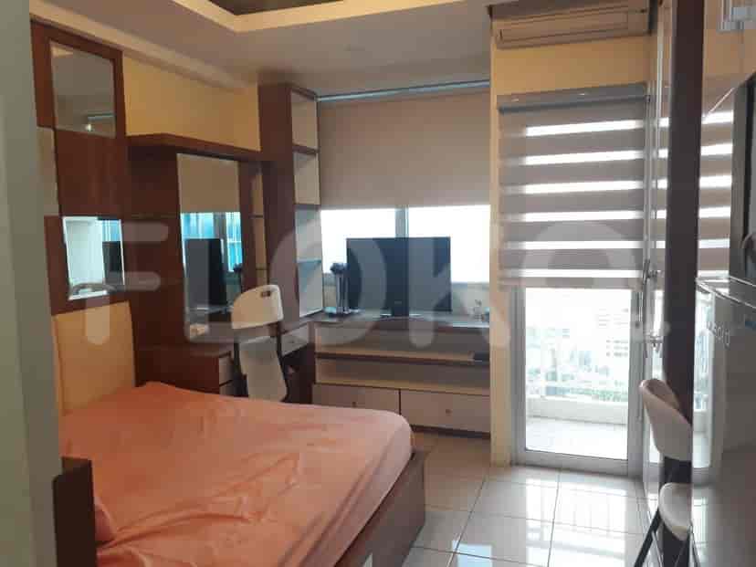 A spacious apartment with a bedroom, balcony, and TV.