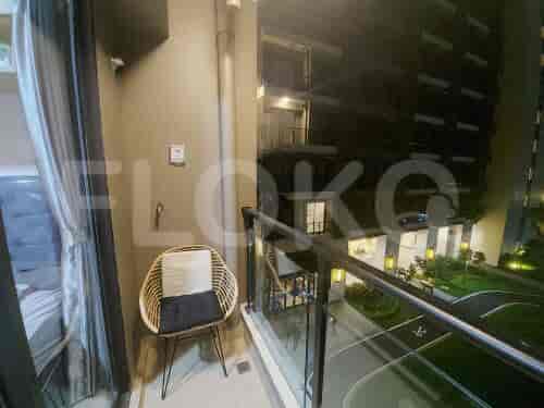 A small balcony with a chair and a view of a building at night.