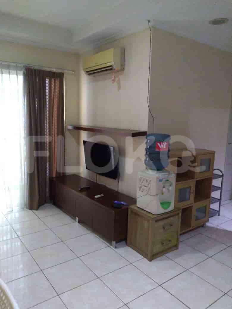Living room with a TV, water dispenser and shelves.