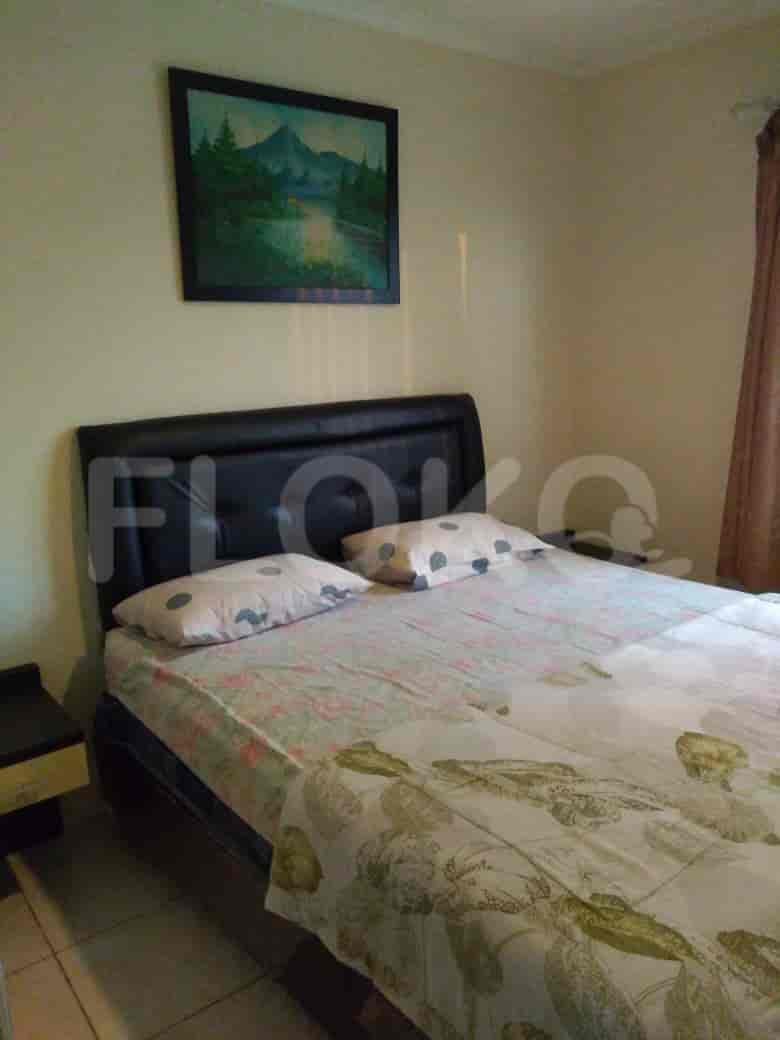 A bedroom with a bed, artwork, and nightstand.