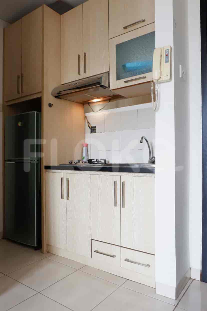 Compact kitchen with wooden cabinets, a refrigerator, and a sink.