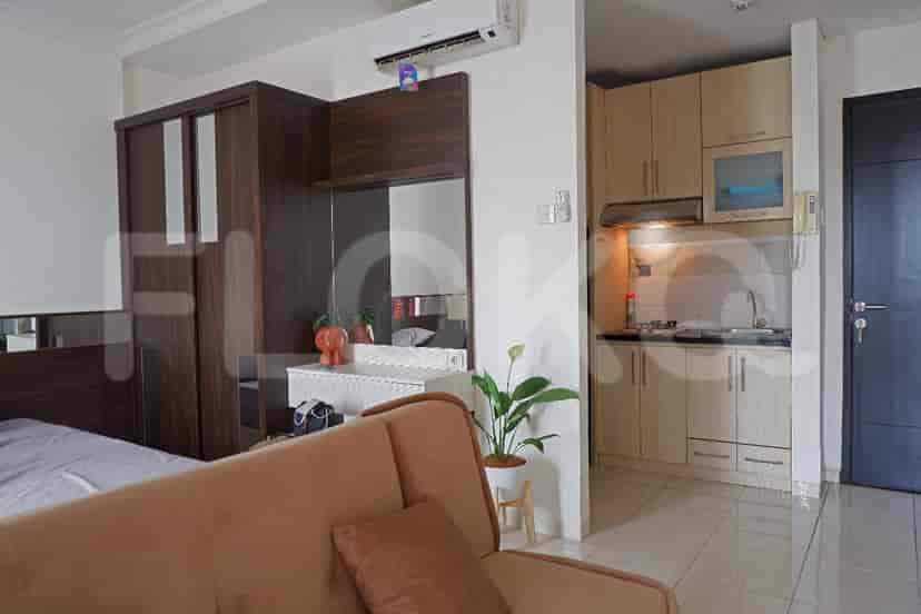 Combined living and kitchen area with a sofa, and kitchen on the side.
