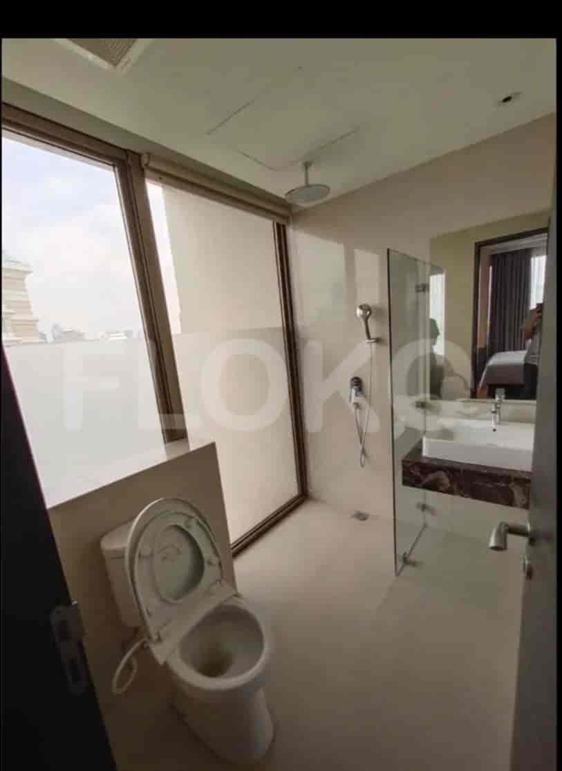 A well-lit bathroom with a glass-enclosed shower, a toilet, and a modern vanity.